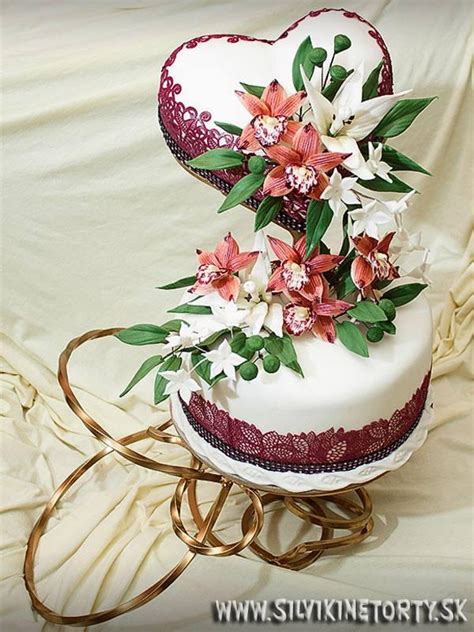 Prezentácia torty na elegantnom stojane, doplnená kvetmi a svetielkami.