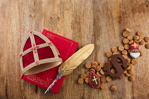 Ilustrácia Sinterklaasa s pomocníkmi rozdávajúcimi darčeky