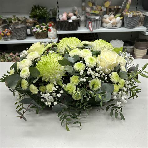 Aranžmán zo zelených listov a bielych kvetov na svadobnom stole