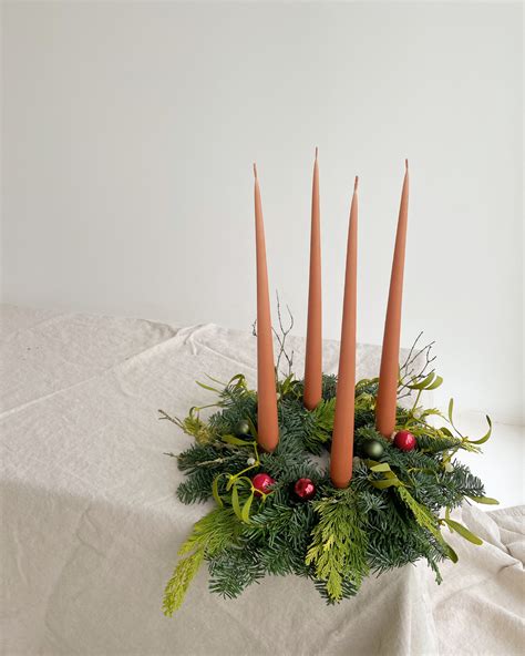 Detailný záber na tradičný malý adventný veniec so štyrmi sviečkami na vianočne prestretom stole