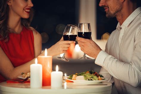 Pár oslavujúci výročie pri romantickej večeri so spomienkovými fotografiami