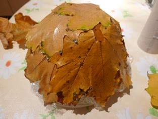 Foto sklenenej nádoby ozdobenej jesennými listami so sviečkou vo vnútri