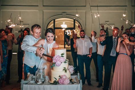 Krájanie svadobnej torty so svietiacimi prskavkami v pozadí