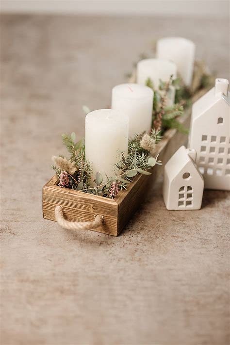 Hotový drevený svietnik zdobený prírodnými materiálmi ako sú šišky a mach