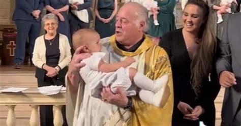 Dieťa s rodičmi a kňazom pri krste, kňaz prikladá krstovú košieľku