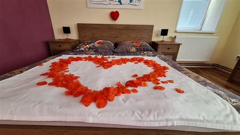 Spálňa s rozsvietenými sviečkami a lupeňmi ruží na posteli