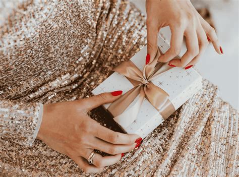 Ilustračná fotografia ženy, ktorá s úsmevom rozbaľuje darček.