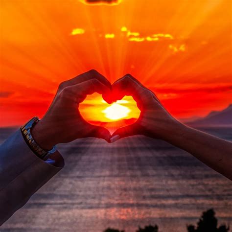 Romantický pár pri západe slnka alebo symbol srdca