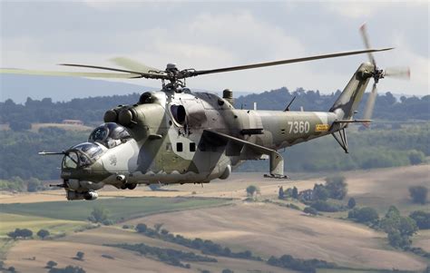 Photo of a Mil Mi-24 Hind in flight over an arid, mountainous region, typical of Afghanistan