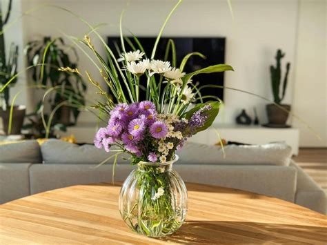 Aranžmán farebných vianočných gúľ a hrdzavých rolničiek vo veľkej sklenenej váze