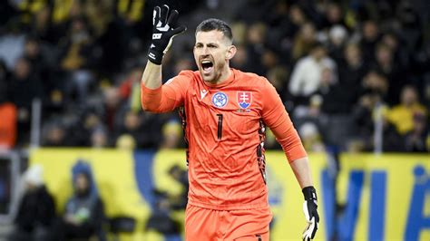 Muž, ktorý sleduje futbalový zápas v televízii, drží v ruke dres obľúbeného tímu.