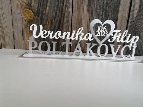 Detailný záber na luxusný kovový svadobný stojan s gravírovanými menami mladomanželov na svadobnom stole.
