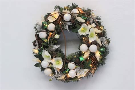 Ukážka vianočne vyzdobeného okenného parapetu s rôznymi dekoráciami a svetielkami.