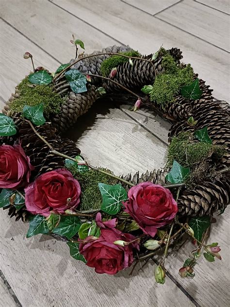 Veniec z halúzok skalníka s červenými plodmi a skalnými ružami