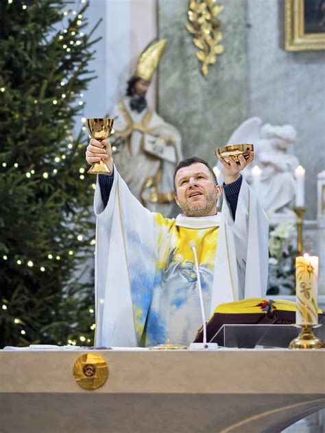 Tematická fotografia: Kňaz krstí dieťa v kostole za prítomnosti krstných rodičov