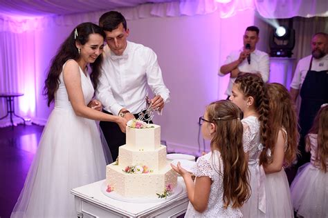 Novomanželia krájajú svadobnú tortu s prepletenými rukami