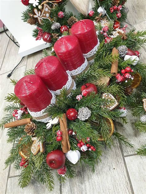 Podlhovastý adventný veniec vytvorený z pohárov naplnených prírodnými materiálmi a sviečkami