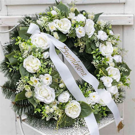 Detailný záber na smútočný veniec v tvare srdca z čerstvých bielych kvetov a zelene