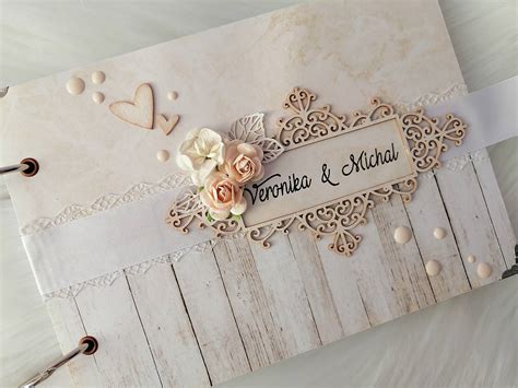 Záber na detailne vypracovaný vintage svadobný fotoalbum na drevenom stole s kvetinovou dekoráciou