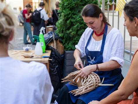 Ľudia rôznych vekových kategórií pri pletení slamených ozdôb na workshope