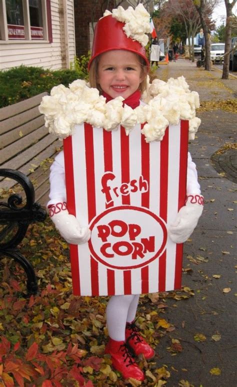 dieťa v kostýme popcornu vyrobenom z kartónovej krabice s bielymi a červenými pásikmi