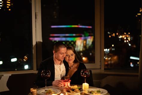 Pár stolujúcich pri sviečkach na romantickej večeri doma