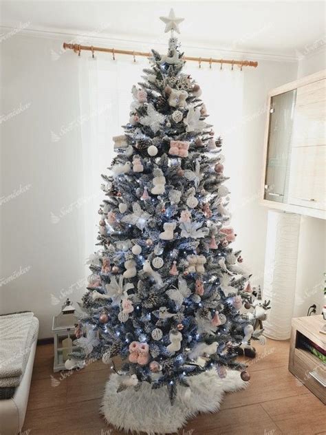 Zasnežený biely vianočný stromček s bielymi ozdobami a strieborno-bielym Santa Clausom