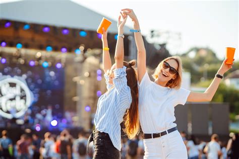 Záber z davu na letnom hudobnom festivale so svetelnou šou a pódiom