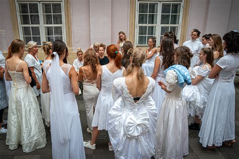 Skupina žien v bielych šatách s tvárami zahalenými šatkami, držiace metly a košíky, prechádzajúce dedinou v zimnom čase