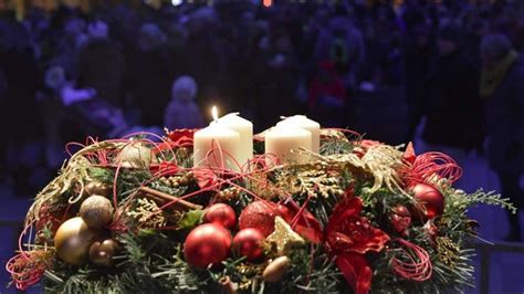Snímka adventného venca so zapálenou prvou sviečkou, ktorá vnáša svetlo do interiéru.