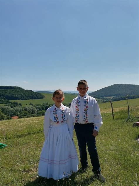 Mladomanželia v tradičných krojoch počas svadobného fotenia v nádhernom prírodnom prostredí.