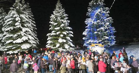 Skupina ľudí spievajúca vianočné koledy pri vianočnom stromčeku s hudobnými nástrojmi