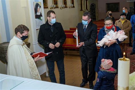 Ilustrácia krstného obradu s kňazom, rodičmi a krstnými rodičmi pri krstiteľnici.