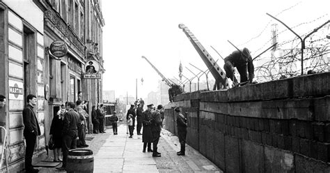 Fotografia Berlínskeho múru s kontrolnými vežami a ostnatým drôtom