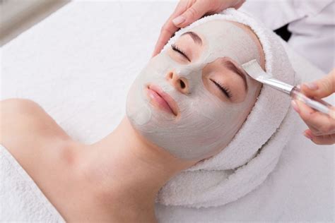 Žena relaxujúca s pleťovou maskou a masážnym prístrojom