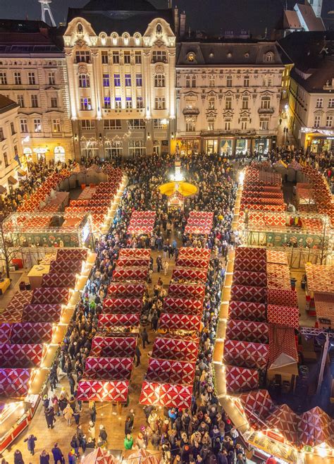 Vianočné stánky na Hlavnom námestí v Krakove s osvetlenou Sukiennicou v pozadí