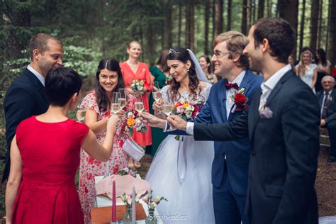 Svadobný pár prechádza uličkou, na nich hádžu okvetné lístky