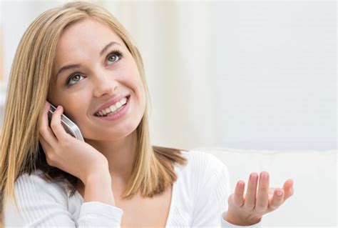 Žena premýšľa, či poslať SMS správu, s telefónom v ruke, zamyslený výraz