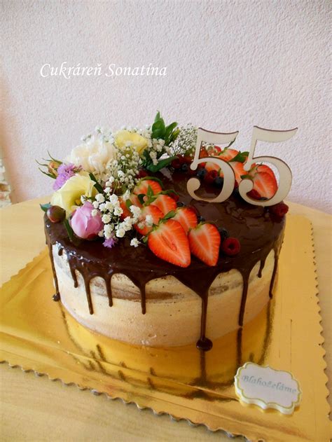 Záber na naked cake zdobený čerstvými jahodami a jedlými kvetmi na drevenom podnose