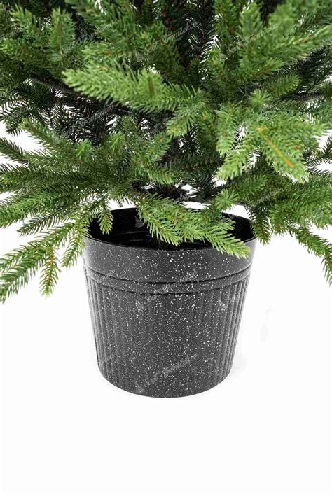 Detail ozdobeného vianočného stromčeka v kvetináči s LED svetielkami a niekoľkými minimalistickými ozdobami.