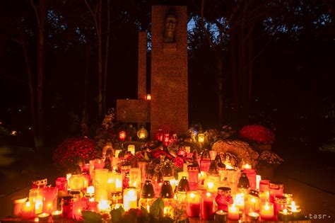 Slovenský cintorín v novembri s horiacimi sviečkami a kvetmi