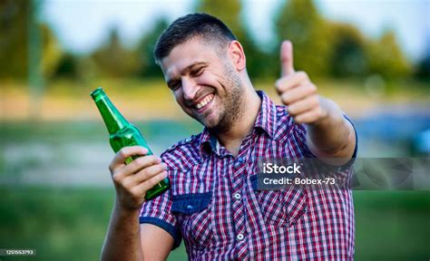 Tematické foto: Muž s úsmevom držiaci pivo alebo drink v neformálnom prostredí