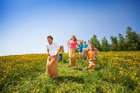 Deti sa zabávajú pri vonkajších hrách - skákanie vo vreciach, frisbee