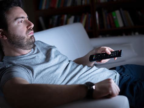 Muž relaxujúci na gauči s teplým čajom a hrejivým vankúšikom
