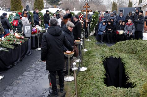 Smútiaci ľudia na pohrebe počúvajúci rečníka