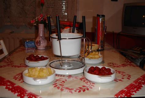 ľudia pri stole s fondue s ovocím a čokoládou