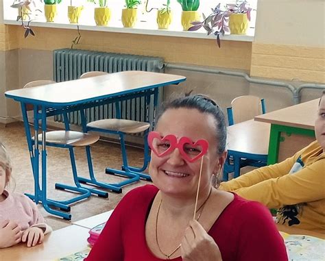 fotografia: skupina prváčikov s veľkými taškami a ich pani učiteľka pred školou