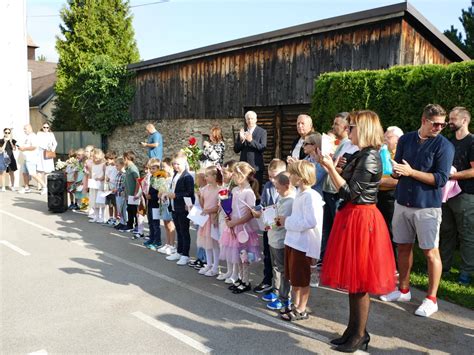 Ilustrácia radostných detí vchádzajúcich do budovy školy v sprievode rodičov a učiteľov