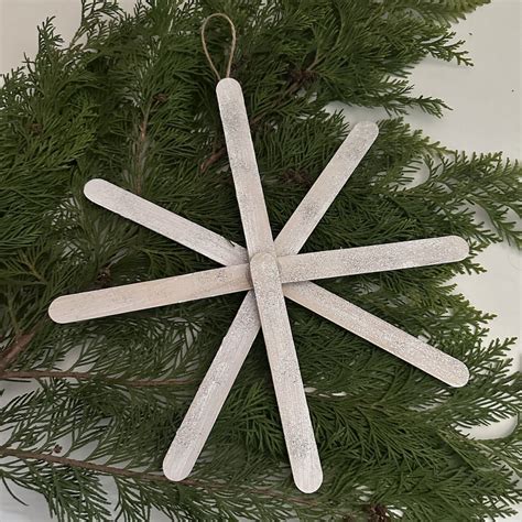 Detail drevených sánok vyrobených z nanukových paličiek, ozdobených zimnými motívmi