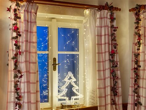 Záber na vkusne vyzdobené vianočné okno s jemným osvetlením a dekoráciami na parapete